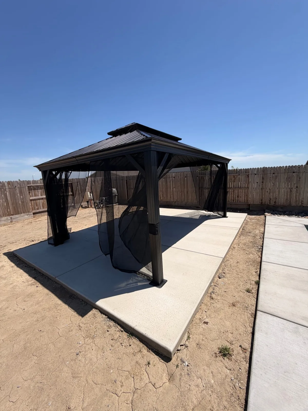Hardtop gazebo assembled on a backyard concrete patio by a California crew