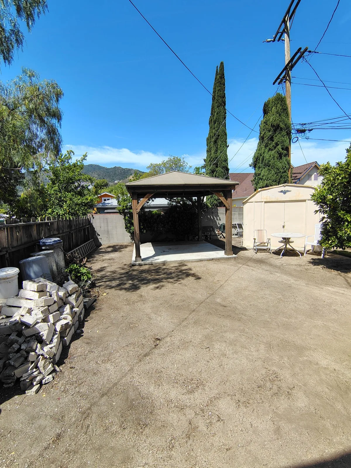 Completed gazebo and pergola assembly on a poured concrete foundation with support posts in a California backyard