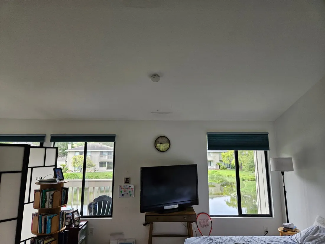 Flat-screen TV mounted on wooden stand in bright bedroom with garden views โ Zomg The Handyman