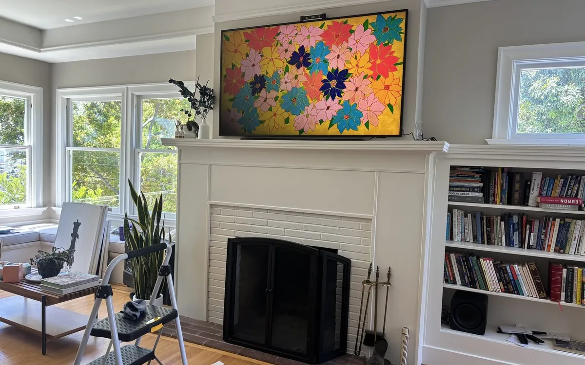 Samsung Frame TV mounted above a fireplace, showing art