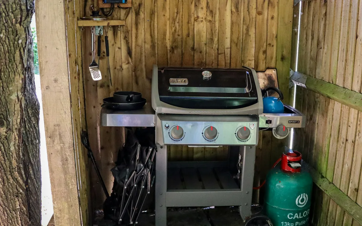 Gas grill under a wooden shelter