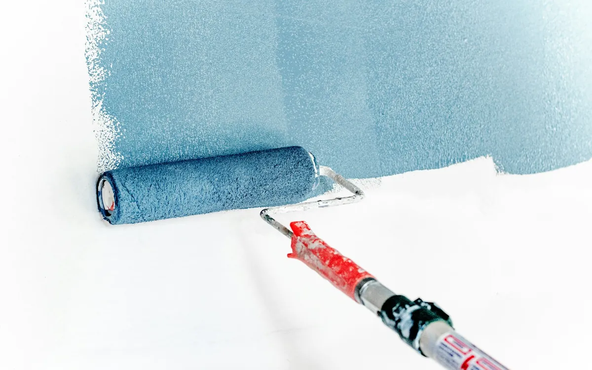 Paint roller applying blue paint