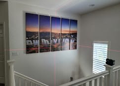Five-panel canvas hung level with laser guides on a stairway wall — Zomg The Handyman
