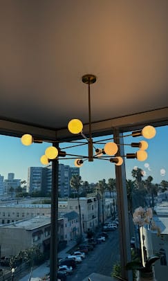 Sputnik chandelier installed against sunset city views through floor-to-ceiling windows — Zomg The Handyman