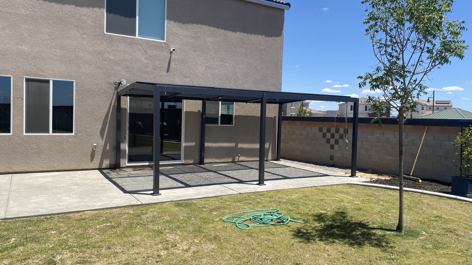 Modern black aluminum pergola assembled over a backyard patio — Zomg The Handyman