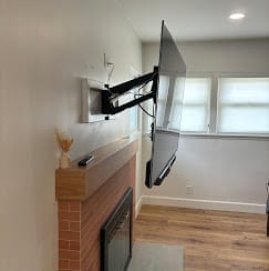 Full-motion articulating TV mount extended above a brick fireplace — Zomg The Handyman