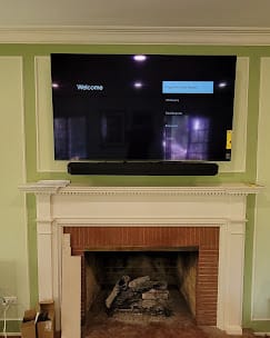 Large TV and soundbar mounted in a recessed alcove above an ornate fireplace mantel — Zomg The Handyman